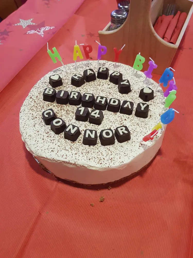 Whole cheesecake topped with grated chocolate and chocolate letters spelling a birthday message